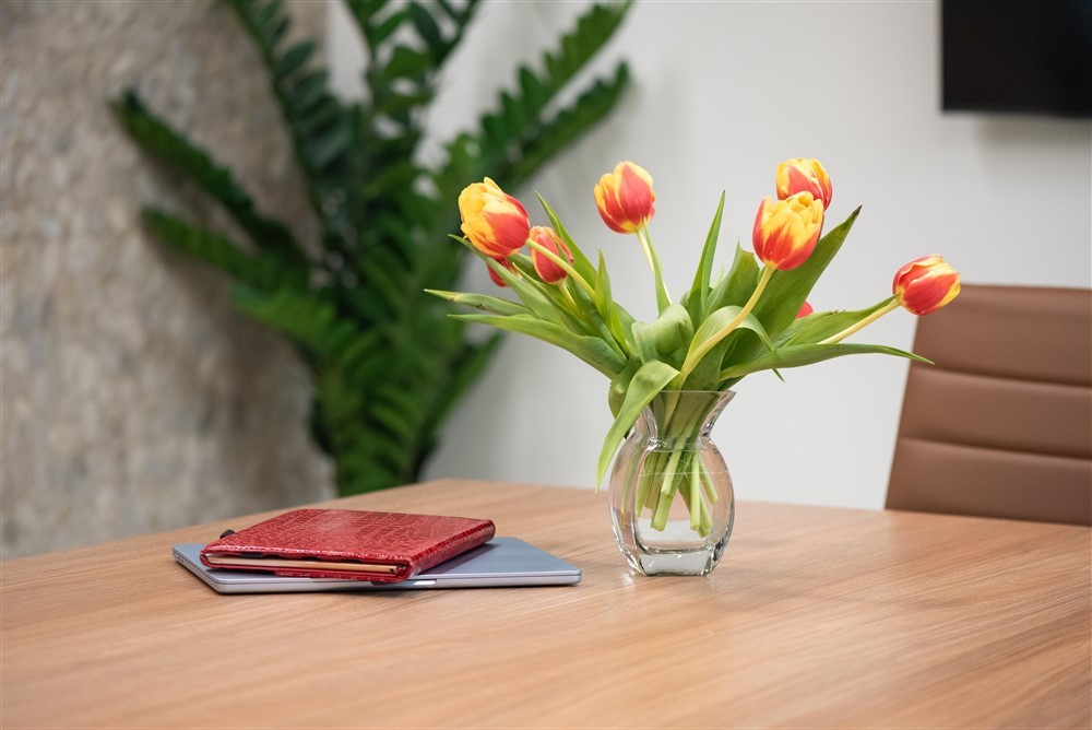 Red-and-yellow tulips beside a red planner and laptop on a conference table.