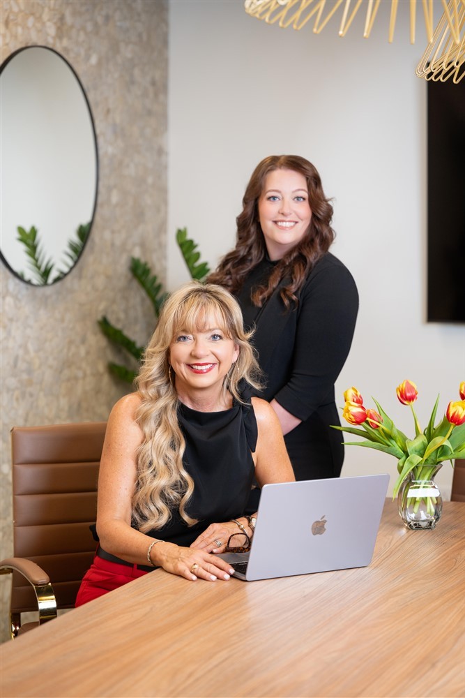 Stacy Harris seated at a conference table with a consulting team member standing behind her.